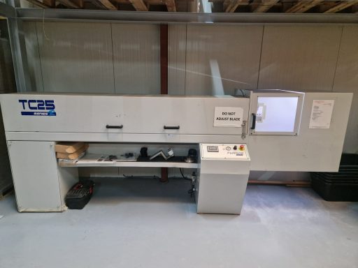 A large, industrial machine with control panel and viewing window, set in a workshop.